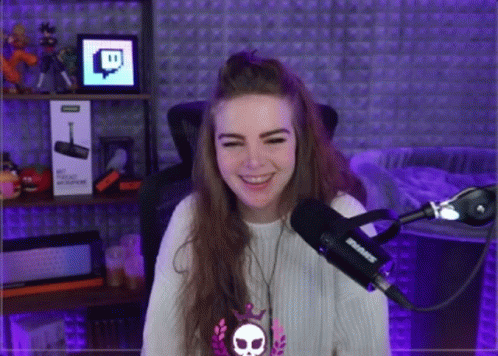 A Girl Is Smiling In Front Of A Shure Microphone . GIF