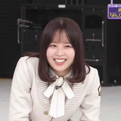 A Girl Is Smiling In Front Of A Sign That Says No GIF