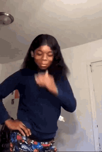 A Girl Is Standing In A Room With Her Hands On Her Hips And Making A Funny Face . GIF
