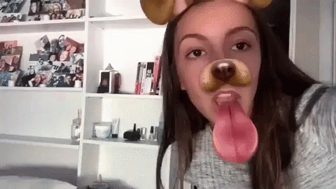 A Girl Is Wearing A Dog Mask With Her Tongue Out . GIF