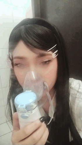 A Girl Is Wearing An Oxygen Mask And Holding A Device GIF