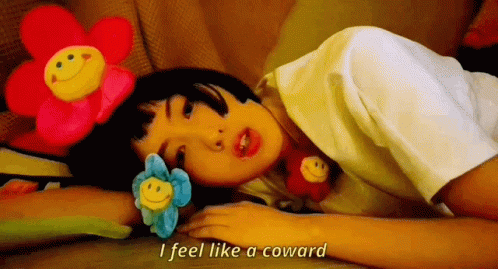 A Girl Laying On The Floor With Stuffed Flowers On Her Head And The Words I Feel Like A Coward GIF
