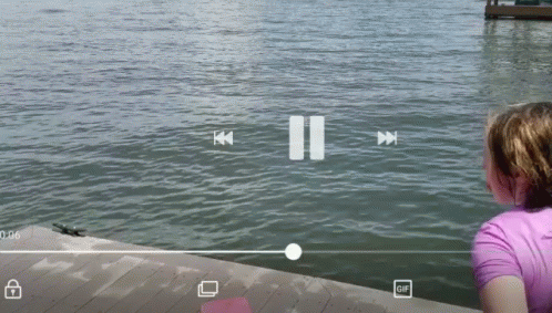 A Girl Looks Out Over A Body Of Water With A Pause Button In The Corner GIF