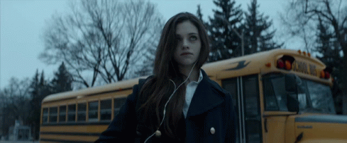 A Girl Standing In Front Of A School Bus GIF