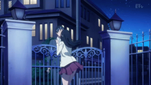 A Girl Stands In Front Of A Building With A Fence And A Sign That Says Nhk E GIF