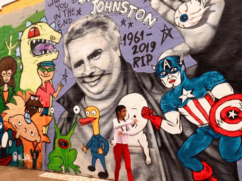 A Girl Stands In Front Of A Mural Of Johnston GIF