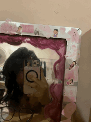 A Girl Taking A Picture Of Herself In A Mirror With A Pink Frame GIF