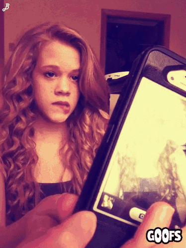 A Girl Taking A Picture Of Herself With A Phone That Says Goofs On The Bottom GIF