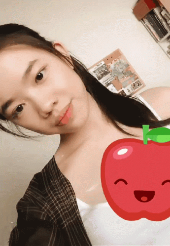 A Girl Taking A Selfie With A Red Apple In The Background GIF