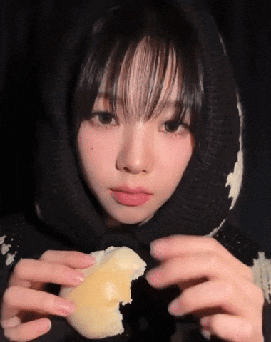 A Girl Wearing A Black And White Sweater Is Holding A Piece Of Cheese In Her Hands GIF
