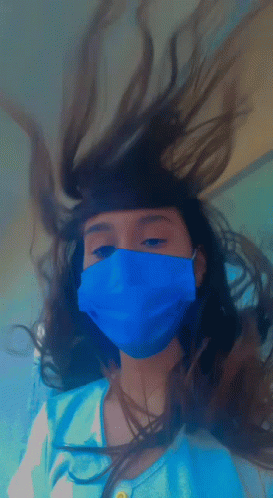 A Girl Wearing A Blue Mask Has Her Hair Blowing In The Wind GIF