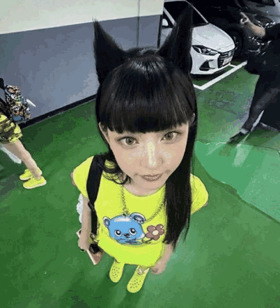 A Girl Wearing A Cat Ear Headband Is Standing In A Parking Garage . GIF