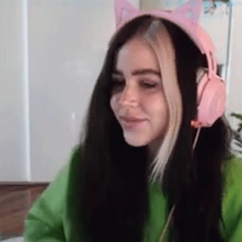 A Girl Wearing A Green Sweater And Pink Headphones With Cat Ears On Her Head . GIF