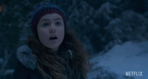 A Girl Wearing A Knitted Hat Is Smiling In The Snow With A Netflix Logo In The Corner GIF