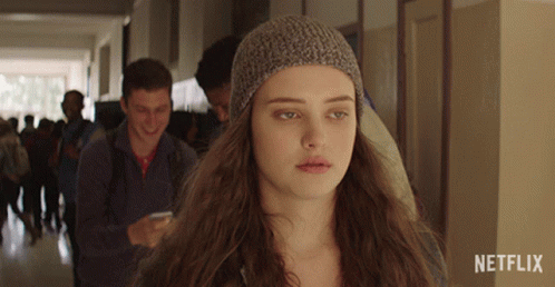 a girl wearing a knitted hat is standing in a hallway with netflix written on the bottom