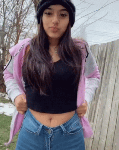 A Girl Wearing A Pink Hoodie And A Black Tank Top GIF