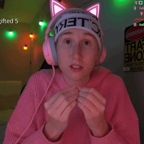 a girl wearing a pink sweater and headphones has a sign that says gifted 5