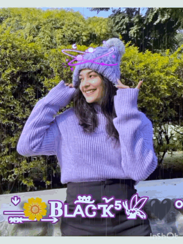 A Girl Wearing A Purple Sweater And A Knitted Hat With The Word Black On It GIF