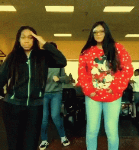 A Girl Wearing A Red Christmas Sweater Is Dancing With Another Girl GIF