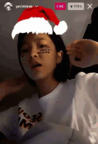 A Girl Wearing A Santa Hat And A T-Shirt That Says ' Merry Christmas ' On It GIF