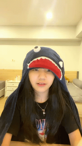 A Girl Wearing A Shark Hat And A Shirt That Says Devil On It GIF