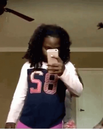 a girl wearing a shirt with the number 58 on it takes a selfie with her phone