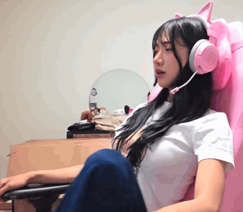 A Girl Wearing A White Shirt And Pink Headphones Sits In A Pink Chair GIF