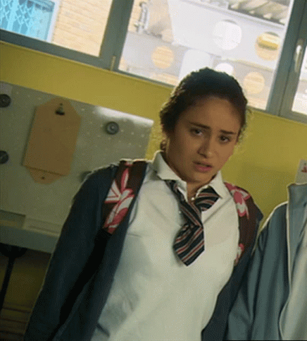A Girl Wearing A White Shirt And Tie With A Backpack On Her Back GIF