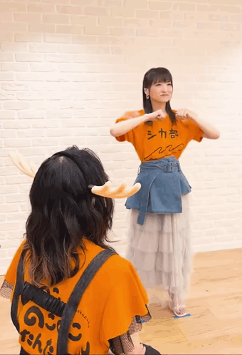 A Girl Wearing An Orange Shirt That Says シカ 部 GIF