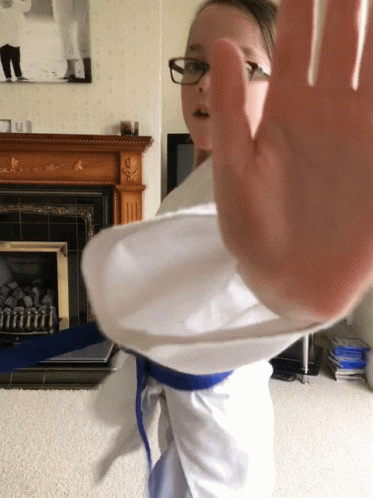 A Girl Wearing Glasses And A Blue Belt Is Making A Stop Gesture GIF