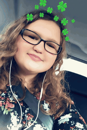 A Girl Wearing Glasses And A Floral Shirt Has Green Clovers On Her Head GIF