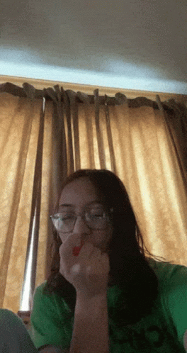 A Girl Wearing Glasses And A Green Shirt Eating A Red Strawberry GIF
