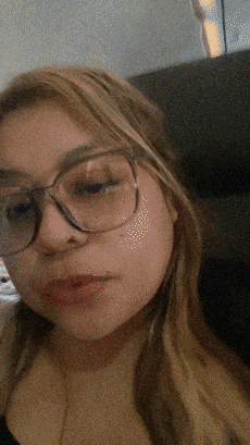 a girl wearing glasses looks at the camera with a blurry background