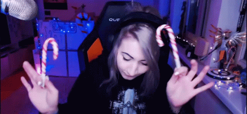 A Girl Wearing Headphones Holds Up Two Candy Canes In Front Of A Microphone GIF