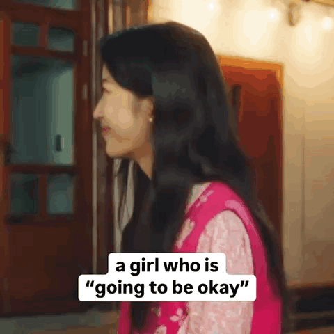 A Girl Who Is Going To Be Okay Is Standing In Front Of A Door And Smiling . GIF