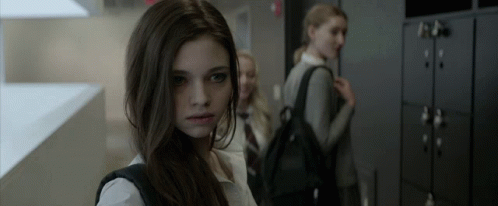 A Girl With A Backpack Is Standing In A Hallway GIF