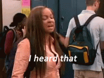 A Girl With A Backpack Is Standing In Front Of A Group Of People And Saying `` I Heard That '' . GIF