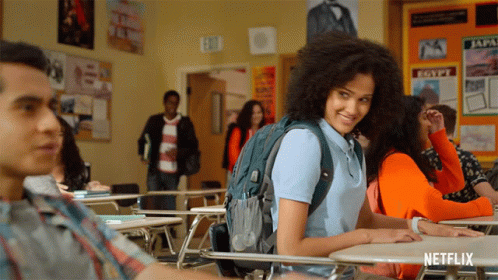 A Girl With A Backpack Sits At A Desk In A Classroom With A Sign That Says Egypt On It GIF
