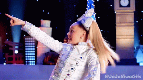 A Girl With A Bow In Her Hair Is Pointing At Something In Front Of A Big Ben GIF