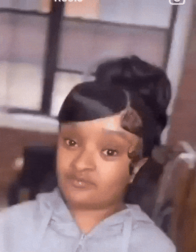 A Girl With A Bun On Her Head Is Looking At The Camera . GIF