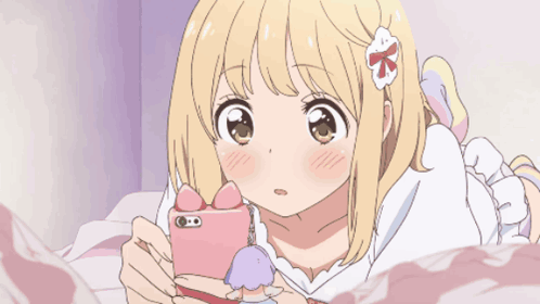 A Girl With A Flower In Her Hair Is Laying On A Bed And Looking At Her Phone GIF