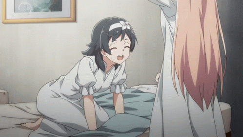 A Girl With A Flower On Her Head Is Kneeling On A Bed Next To Another Girl GIF