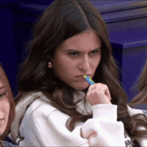 Girl With Green Pen In Mouth Looking At Camera GIF