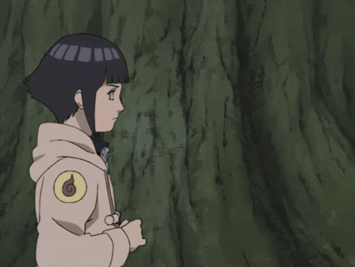 A Girl With A Hooded Jacket Is Standing In Front Of A Tree With Her Hands Together GIF