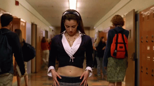 A Girl With A Red Backpack Is Standing In A Hallway With Other People GIF