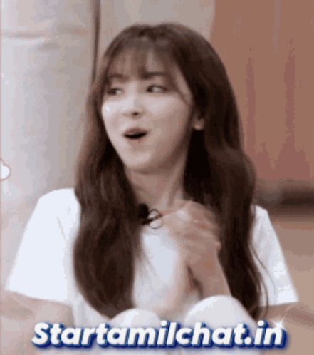 A Girl With A Surprised Look On Her Face Is Sitting In Front Of A Sign That Says Startamilchat.in GIF