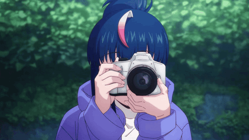 A Girl With Blue Hair Is Holding A Camera In Front Of Her Face GIF