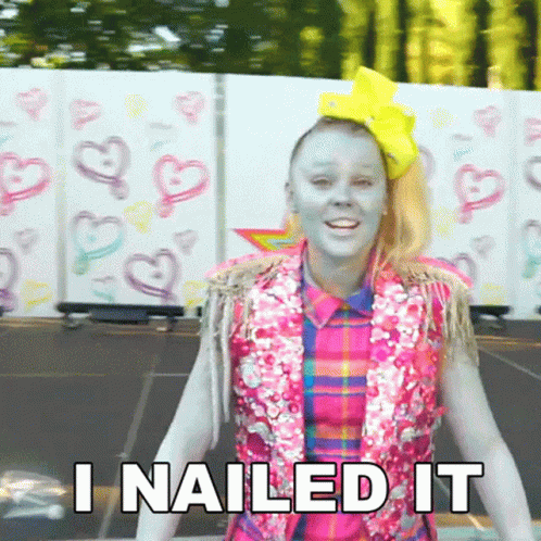 A Girl With Blue Paint On Her Face Is Standing In Front Of A Wall That Says I Nailed It . GIF