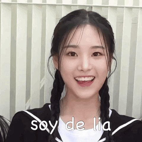 A Girl With Braids Is Smiling And The Words Soy De Lia Are On Her Shirt . GIF
