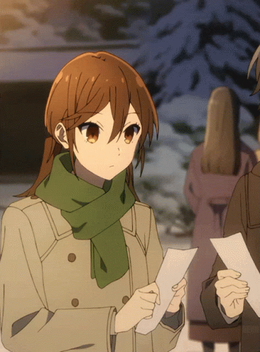 A Girl With Brown Hair And A Green Scarf Holds A Piece Of Paper GIF